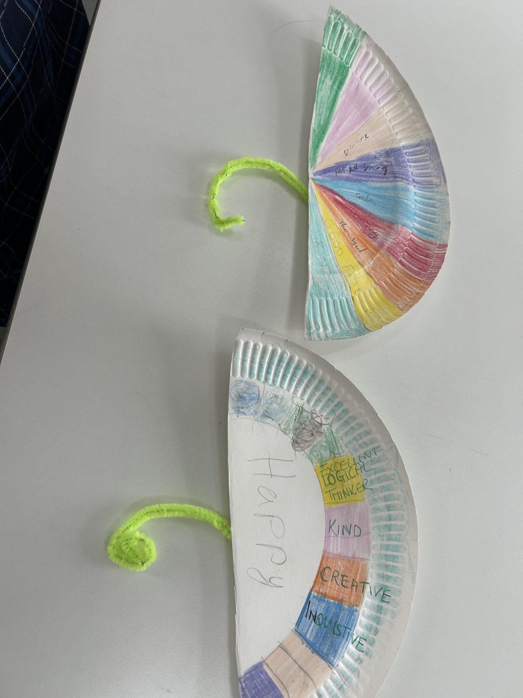 Two paper plate strength wheels coloured in segments labelled happy, kind, creative, inquisitive and excellent logical thinker