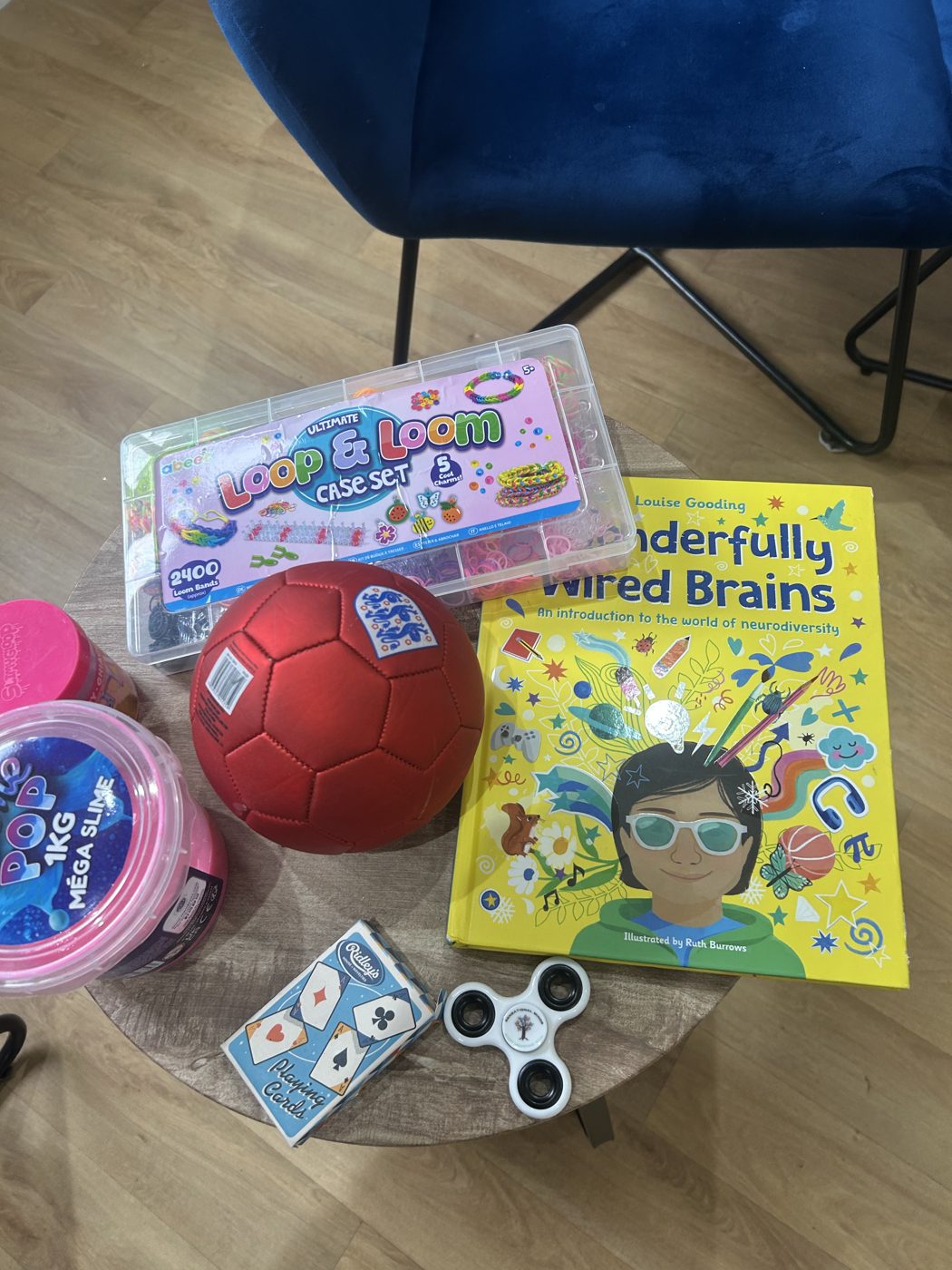 A coaching side table holding loom bands, a football, slime, playing cards, a fidget spinner and the book Wonderfully Wired Brains